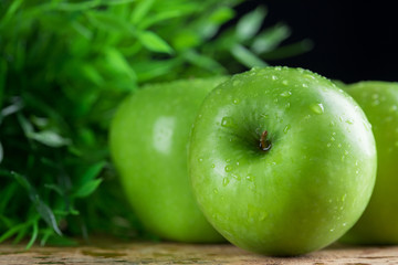 Ripe green apples with water dropletson wooden background
