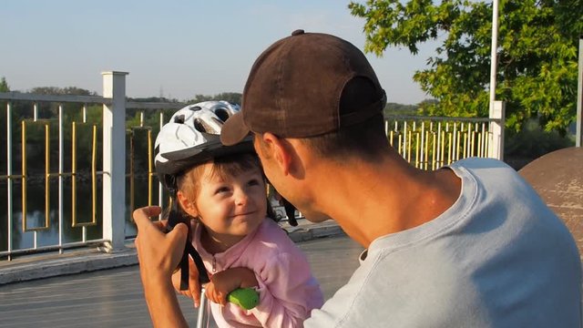 The child is wearing a helmet. The parent wears a helmet on the child.