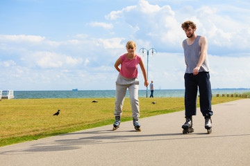 Young pair riding rollerblades in park.