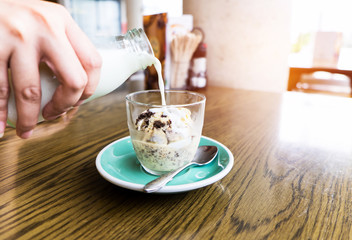 Hand pouring milk into bowls with cookie and cream icecream