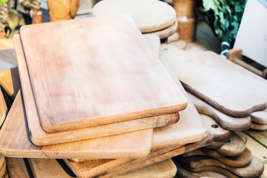Many handmade wooden cutting boards of different size and shape. A stack of rustic brown chopping boards from natural untreated wood. Folk craft, woodworking concept