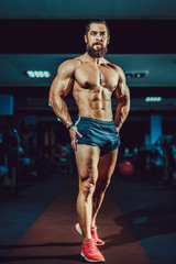Athlete muscular bearded bodybuilder man with naked torso posing in gym.