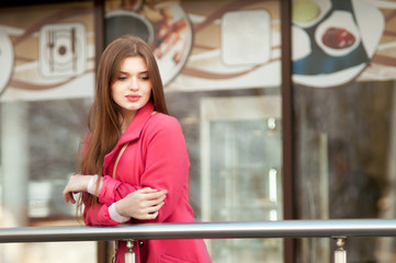 woman in pink coat waiting bye at the window of the restaurant
