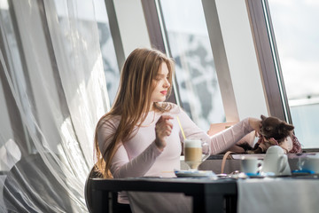girl  drinking a latte and petting a small dog