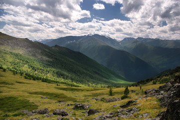 Mountain ranges and valley with forest view from above top height with rocks and alpine meadow in the foreground  Altai Mountains Siberia, Russia