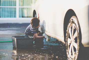  asian child washing a car on summer day