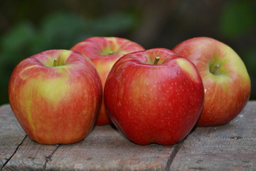 Red ripe apples on a wooden surface.