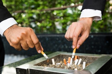 close up hand businessman two person cigarettes for smoking stand in the smoking zone area.