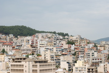View of an agglomerated cityscape with modern style residelntial aartment buldings. Neutral pastel color cityscape with a patch of forest in the background.