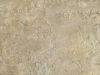 Old beige wall covered with uneven plaster. Texture of vintage shabby sand stone surface, closeup.