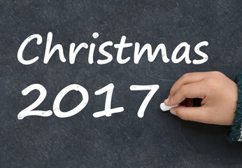 Fototapeta premium Little boy writing Christmas 2017 on a blackboard