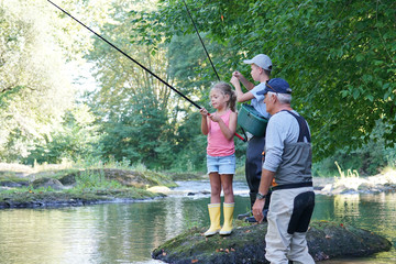 Dad teaching kids how to fish in river