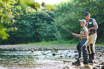 Father teaching son how to fly-fish in river