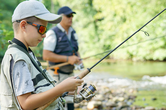 Portrait of young boy learning how to fish with daddy