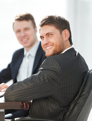 successful businessman with his colleague sitting behind a Desk.