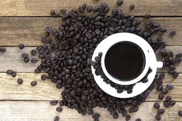 Coffee beans and black coffee cup on wood background. Top view with copy space for your text