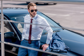 businessman leaning on car