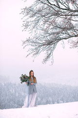 Beautiful winter portrait of young woman in the winter snowy scenery.