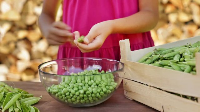 Young girl hands shelling peas, closeup - camera slide, track subject