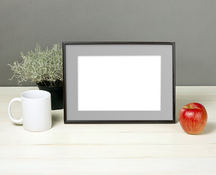 Frame mockup with plant pot, mug and apple on wooden shelf