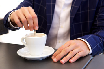 Fototapeta na wymiar Close up businessman stirring hot coffee at cafe