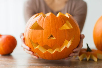 close up of woman with halloween pumpkin at home