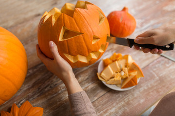 close up of woman carving halloween pumpkin
