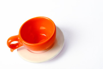 An empty orange cup with white plate isolated on white background.