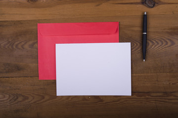 Top view of envelope and blank greeting card on  wooden background. Desktop with blank page mock up, open envelope , Creative concept, empty greeting card