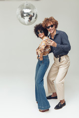 Emotional smiling retro loving couple dancing near disco ball.