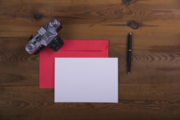 Top view of envelope and blank greeting card with camera on  wooden background. Desktop with blank page mock up, open envelope , Creative concept, empty greeting card
