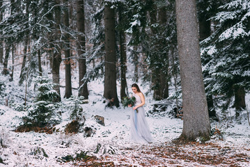 Beautiful winter portrait of young woman in the winter snowy scenery.