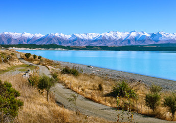 The  country road along the Lake Tekapo and snowy mountains in  autumn, Canterbury, South Island, New Zealand.