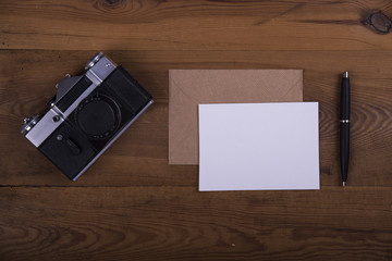 Top view of envelope and blank greeting card with camera on  wooden background. Desktop with blank page mock up, open envelope , Creative concept, empty greeting card