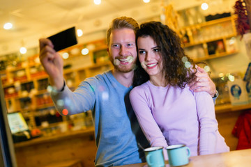 Happy couple taking selfie in coffee shop