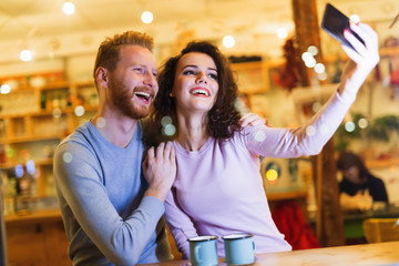 Obraz na płótnie Canvas Happy couple taking selfie in coffee shop