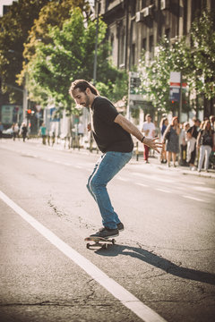 Pro skateboard rider in front of car on city road