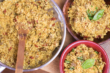 Bulgur or pilaf or risotto or East barley porridge with mushrooms and vegetables and basil in ceramic pottery bowl with chopsticks rustic style on rural wooden table
