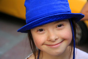 Cute smiling down syndrome girl on the background of taxi