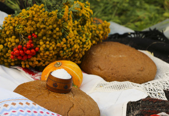 Autumn still life - loaf, pumpkin, mountain ash, tansy, wheat ears, salt,.on a white tablecloth with lace