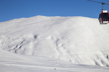The mountain slope of the ski resort is striated by freeride trails.  A lonely snowboarder at the...
