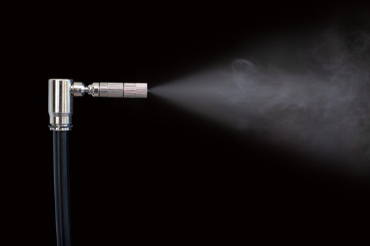 Nozzle sprays liquid into vapor black background