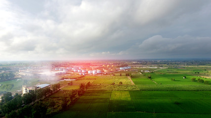 Oil refinery factory in the middle of green fields under the beautiful cloudscape.