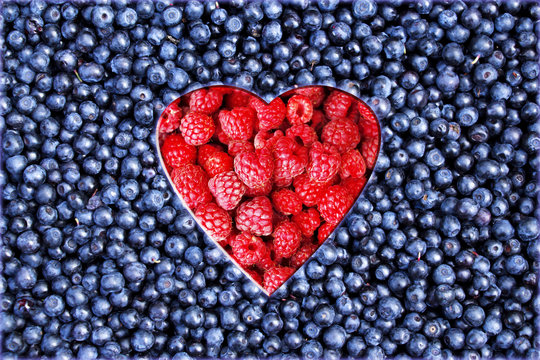 Heart from raspberries on a background of fresh ripe blueberries.