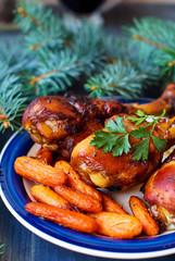 Chicken legs baked in honey and soy sauce with baked carrots Christmas recipe, decorated with fir branches.