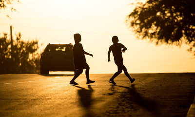 children run across the road at sunset