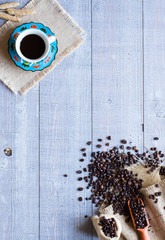 Coffee beans and cup of coffee with other components on different wooden background.  Free space for text