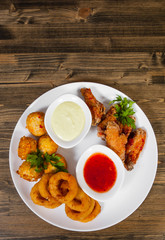 set of appetizers. salted balls, chicken wings, onion rings, sauce on a wooden background. with copy space. top view
