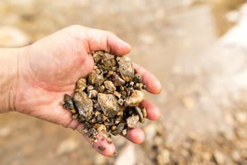 Small stones in the hand on the pond