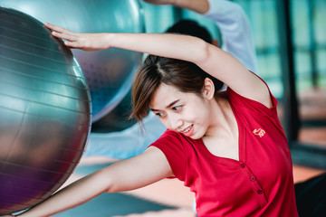 Naklejka premium Asian teenage girl exercises with a fitness ball in the fitness center with happiness.